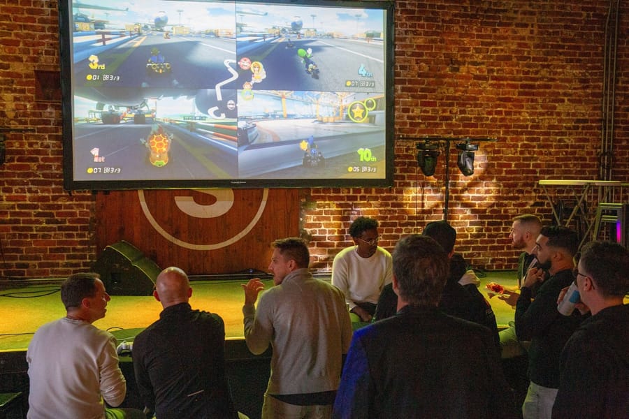 Joybreak guests watching a four-player Mario Kart race on a big screen at a social night in downtown Orlando
