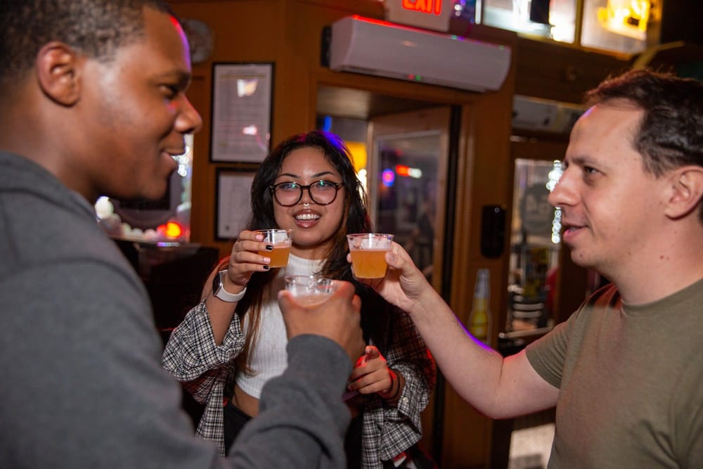 Three friends clinking glasses and smiling at a Joybreak meetup in Orlando